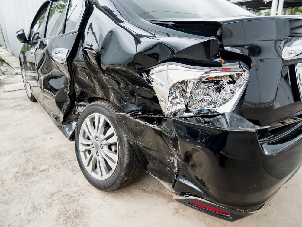 Ein schwarzes Auto mit starken Schäden am Heck, zerbeultem Blech und einem zerbrochenen Rücklicht